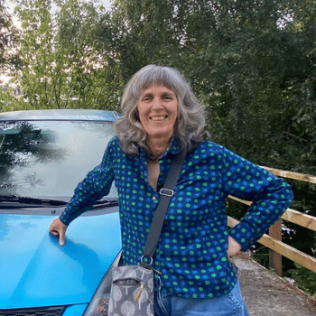 Alison standing next to blue car