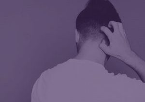 Back of mans head, white t-shirt, man itching his neck/head, purple hue over the entire image